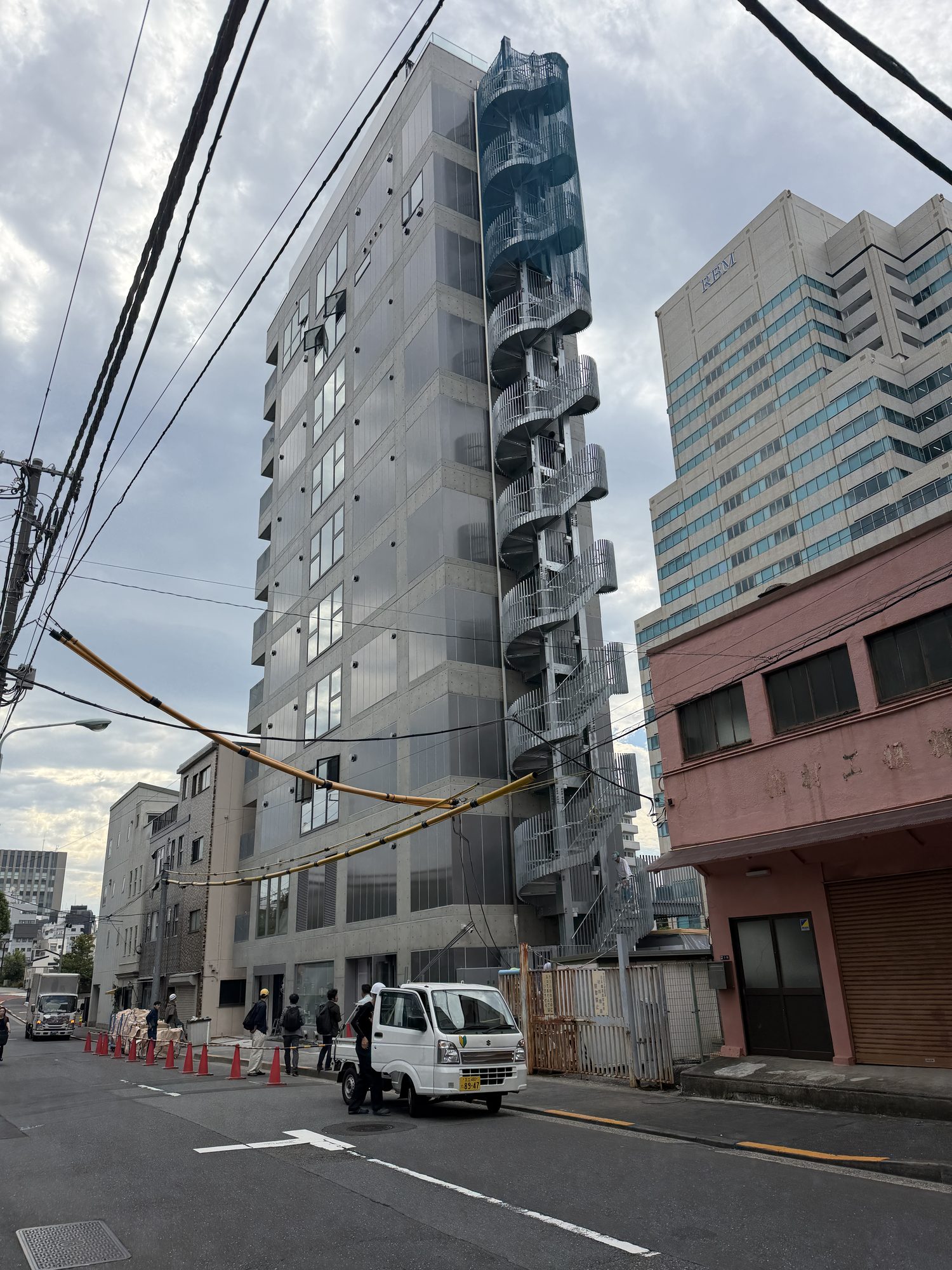 道路側から見上げる。外壁に沿って螺旋階段が立ち上がる